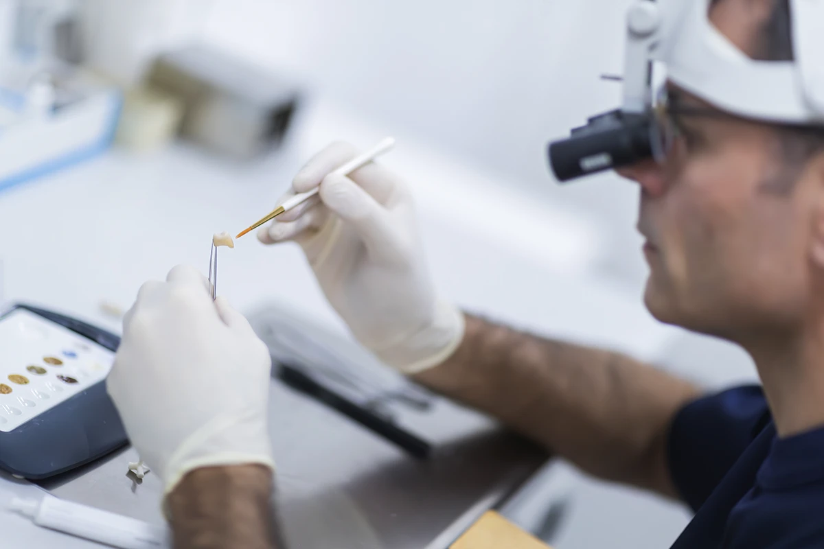 Dottor Giuliodori 
                lavora con attenzione su un dente utilizzando strumenti odontoiatrici in uno studio 
                moderno e ben illuminato. L ambiente trasmette professionalità e cura per il paziente.